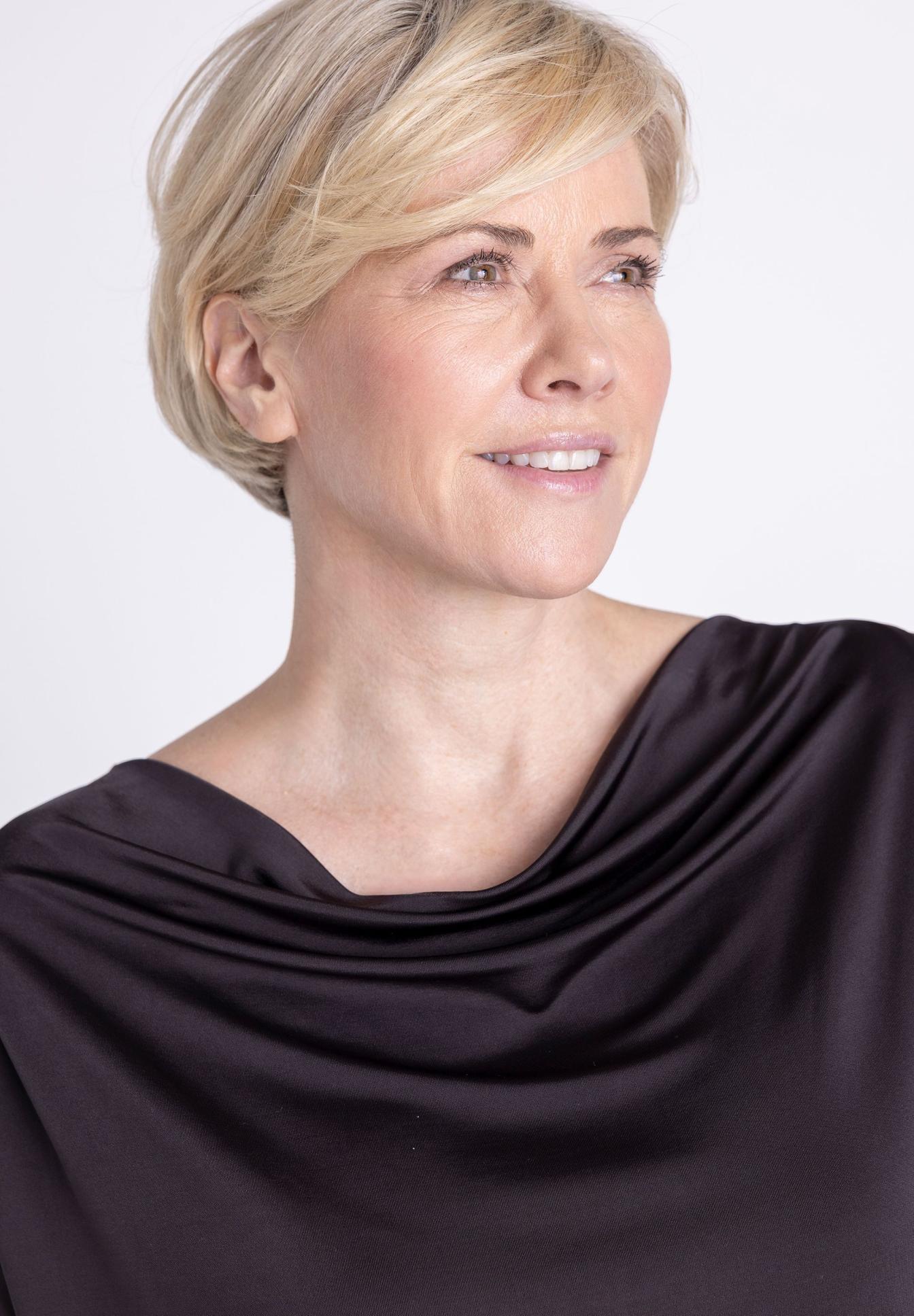 Damenlook, haare kurz, blinkendes Gesicht, schwarzes Oberteil, Drapierter Knoten