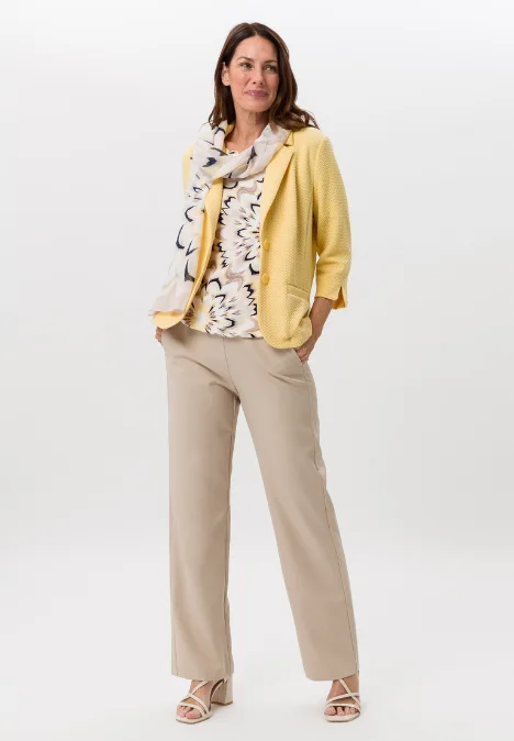 Dame mit gelber Jacke, bemusterten Shirt und beiger Hose